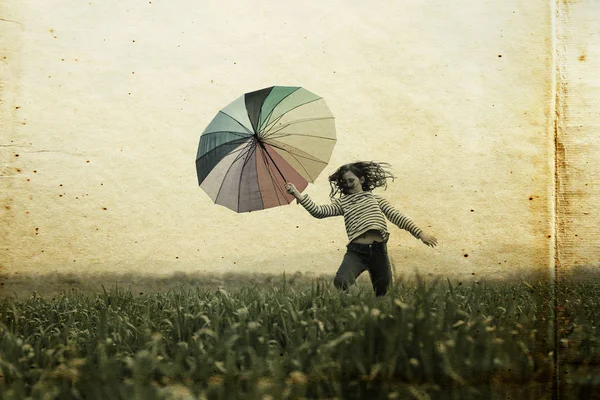 Menina com guarda-chuva pulando no campo — Fotografia de Stock