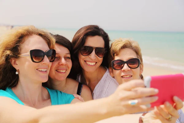 Retrato de cuatro mujeres de 40 años en la playa — Foto de Stock