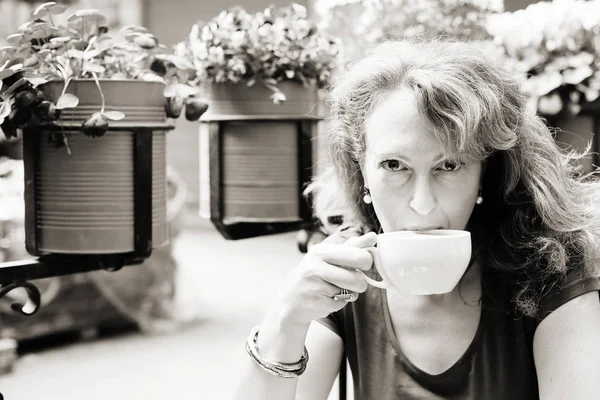 Зрелая женщина сидит в кафе на открытом воздухе — стоковое фото