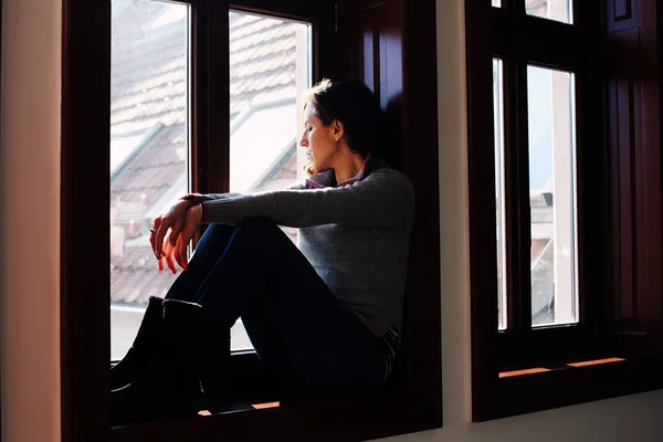 Smutná žena hledá přes okno — Stock fotografie