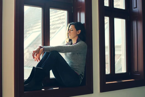 Treurige vrouw zoekt via venster — Stockfoto