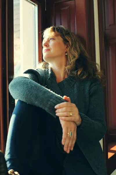 Mujer madura mirando por la ventana —  Fotos de Stock