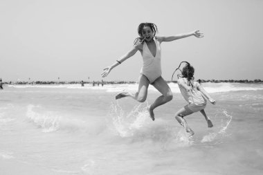 young girls jumping on seaside clipart