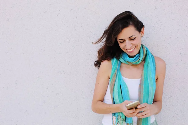 Beautiful woman standing against of city grey wall with mobile p — Stock Photo, Image