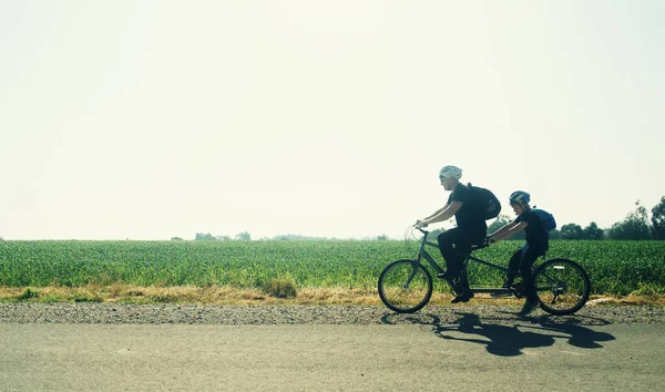 Padre e hijo montan en una bicicleta tándem — Foto de Stock