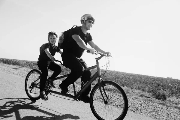 Padre e hijo montan en una bicicleta tándem —  Fotos de Stock