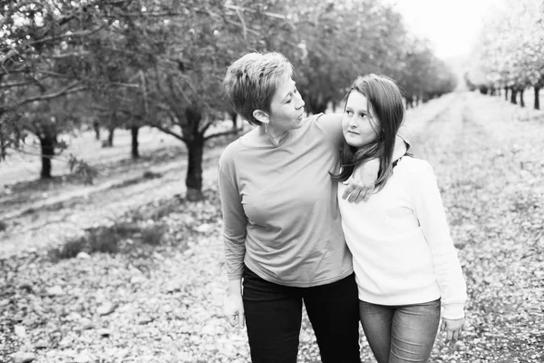 幸せな母と娘の昼間で春満開の公園を歩いて — ストック写真