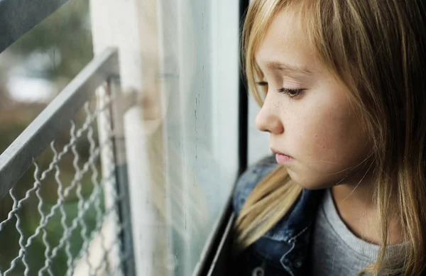 Portrett av en 9 år gammel trist jente som sitter ved siden av en windo – stockfoto