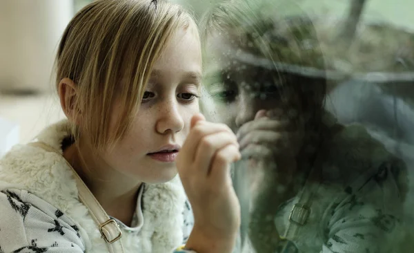 Retrato de uma menina triste de 9 anos que está sentada ao lado de um windo — Fotografia de Stock