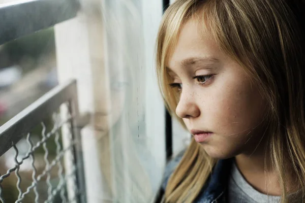 Retrato de uma menina triste de 9 anos que está sentada ao lado de um windo — Fotografia de Stock