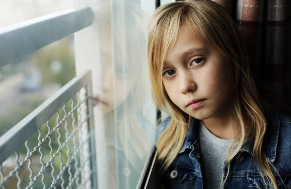 Retrato de una niña triste de 9 años que está sentada junto a un windo — Foto de Stock