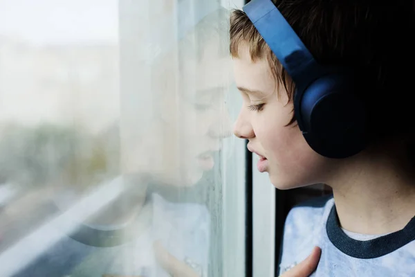Nastolatek 12 lat chłopiec patrząc przez okno na deszcz — Zdjęcie stockowe