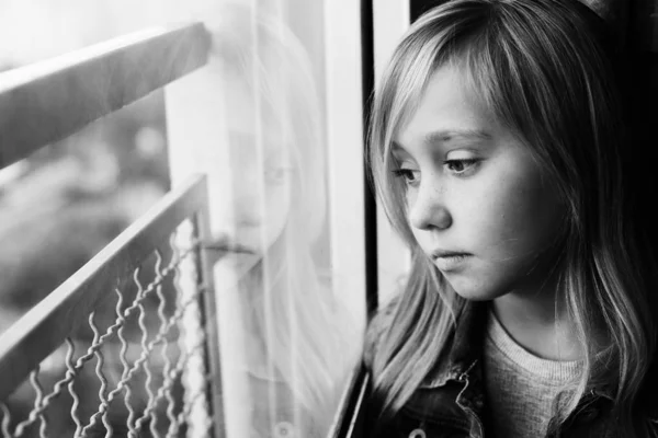 Porträt eines 9-jährigen traurigen Mädchens, das neben einem Windo sitzt — Stockfoto