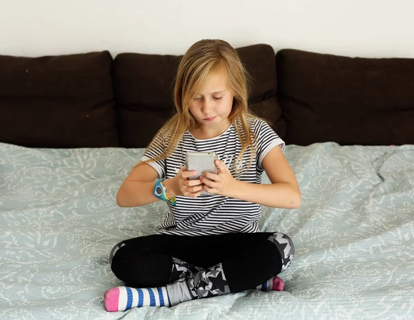 Covid-19. Home school concept. 9 year old girl is bored at home with a mobile phone.