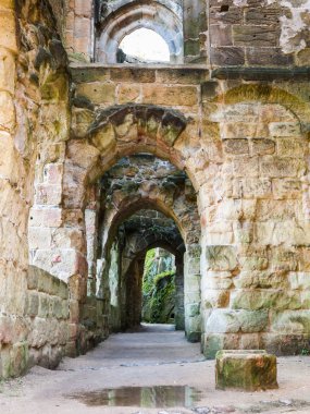 Taş duvarları ve kemerleri olan koridor.