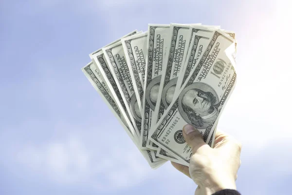 Рука держит доллар США против голубого неба — стоковое фото