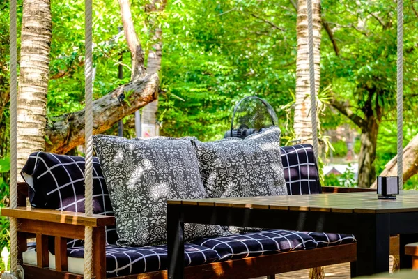 Красочная подушка на деревянном стуле с тканевой подушкой в саду на — стоковое фото
