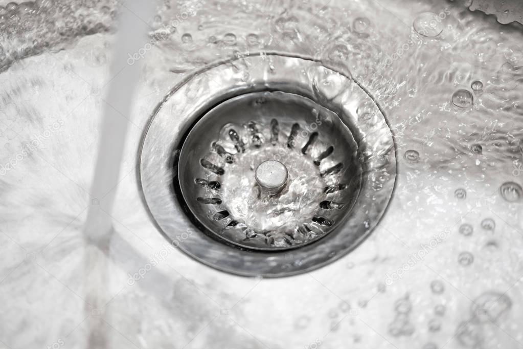 Stainless steel sink plug hole close up with water