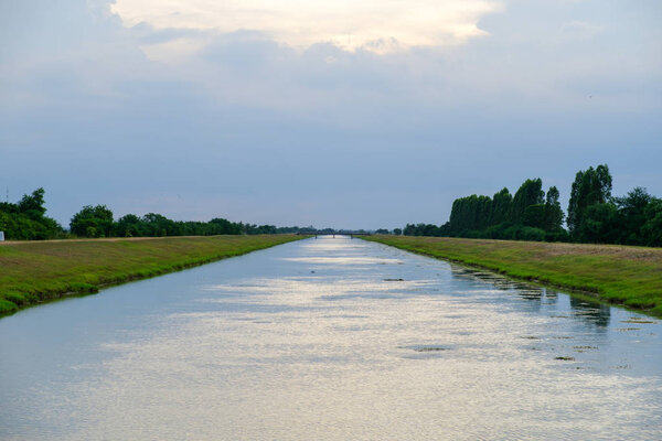 Water flowing canal for paddy irrigation with skies in Thailand