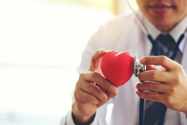 Lekarz trzymając się za ręce z czerwonym sercem w klinice office, zdrowe li — Zdjęcie stockowe