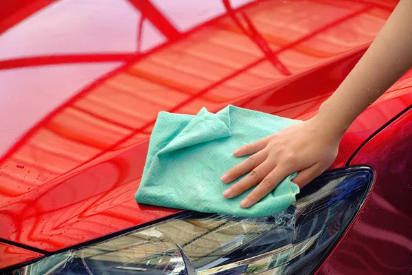 Hand vrouwen houd water boven de rode auto voor het wassen met microfib — Stockfoto
