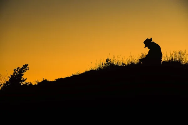 Silhouette man spread hand on top of a mountain enjoying sunset. — Stock Photo, Image