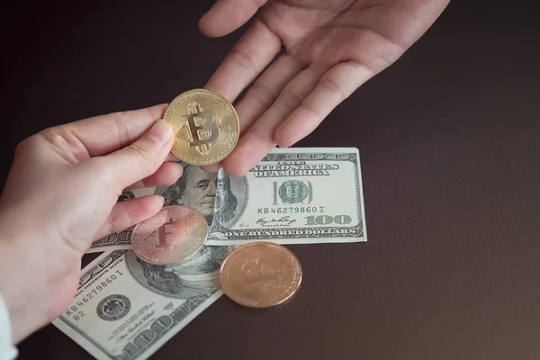 Рука дает биткойн на банкнотах в сто долларов. Обмен — стоковое фото