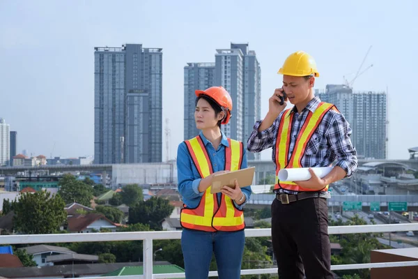 Ingenieros de hombres se paran en edificios altos y hablan de teléfonos celulares —  Fotos de Stock