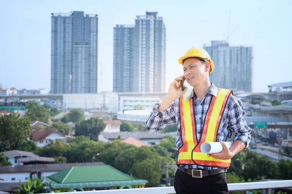 Ingenieros de hombres se paran en edificios altos y hablan de teléfonos celulares —  Fotos de Stock