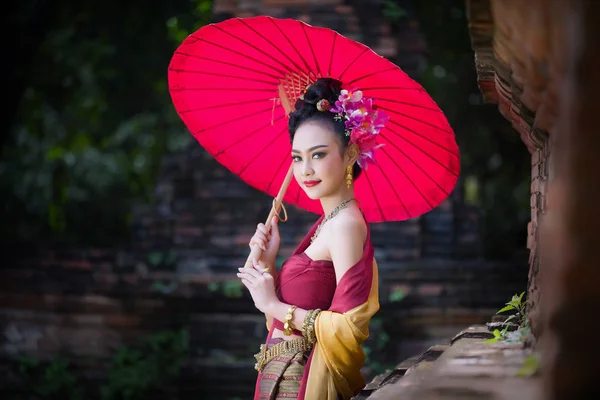 Schöne thailändische Mädchen in traditioneller Kleidung Kostüm roten Regenschirm als — Stockfoto