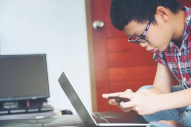 Sevimli çocuk oyna cep telefonu ve laptop arıyor, 