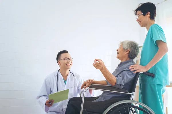 Médico segurando a mão do paciente idoso em um wheelchai, dando su — Fotografia de Stock