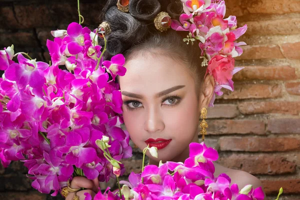 Thailändische Frau trägt typisches thailändisches Kleid mit Blumenhintergrund, — Stockfoto