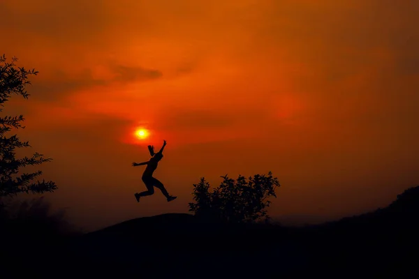 Silhouette of young woman jumping against sunset with copy space — Stock Photo, Image