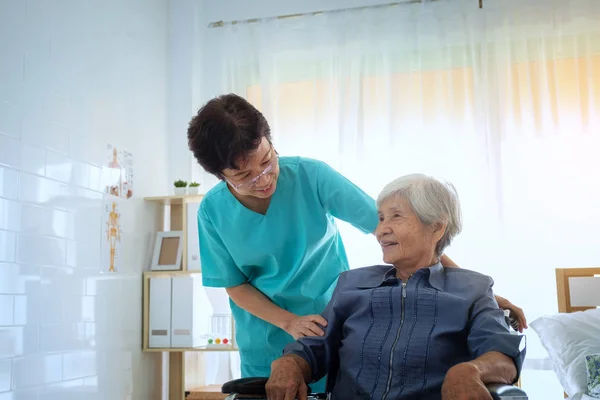 Erfreut positive Pflegerin hilft ihrem Patienten, Krankenschwester umarmt — Stockfoto