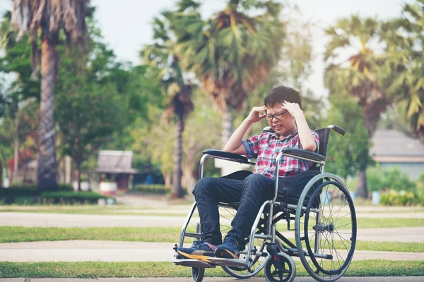 Alleen Azië jongen in rolstoel na een hoofdpijn in het park — Stockfoto