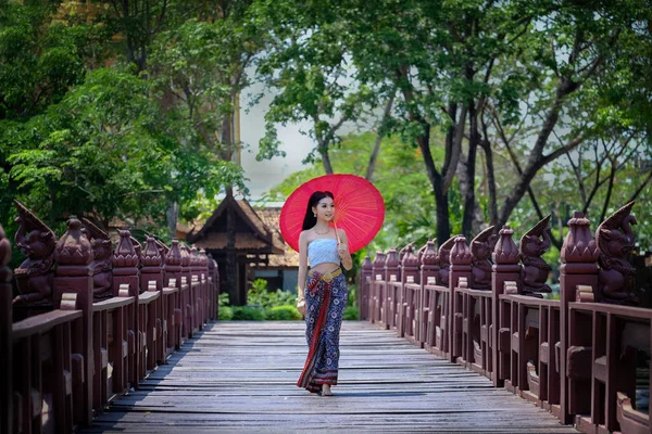 Hermosa chica tailandesa en traje de vestido tradicional paraguas rojo como — Foto de Stock