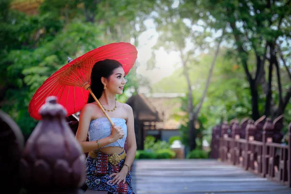 Hermosa chica tailandesa en traje de vestido tradicional paraguas rojo como — Foto de Stock