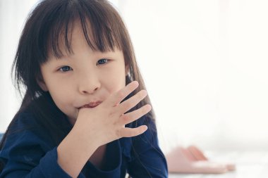 Asyalı tatlı kız parmağını emiyor.