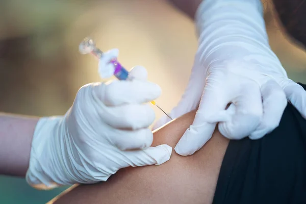 Close up of doctor injecting flu vaccine to patient\'s arm in local home