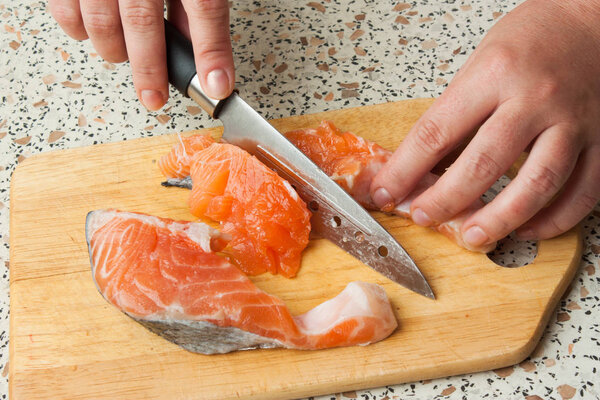 человеческие руки, разделывающие лосося
