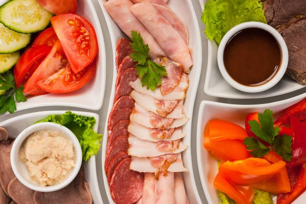 Plato con diferentes tipos de salchichas y jamón con verduras —  Fotos de Stock