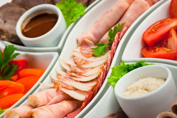 Plato con diferentes tipos de salchichas y jamón con verduras — Foto de Stock