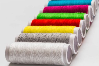 Beyaz bir arka plan üzerinde renkli iplik bobin yukarıya kapatmak