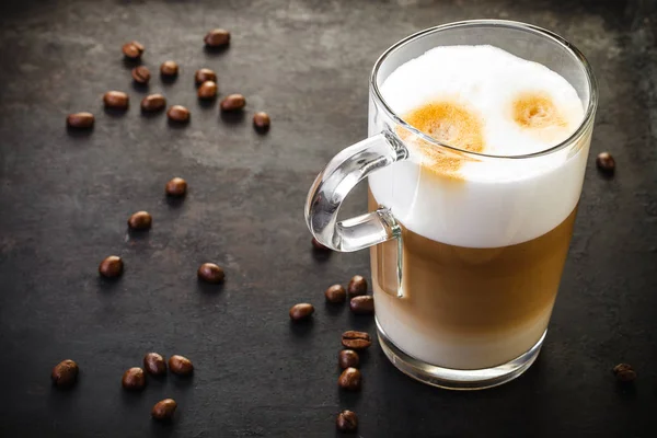 Dos vasos de latte y cucharas sobre fondo rústico oscuro —  Fotos de Stock