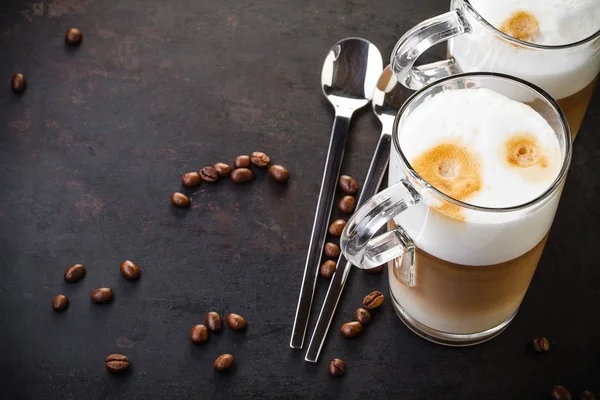 Två glas latte ad skedar på mörk rustik bakgrund — Stockfoto