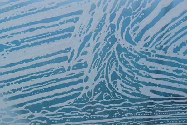 Sabun köpük desen ve kabarcıklar camına. Mavi arka plan.