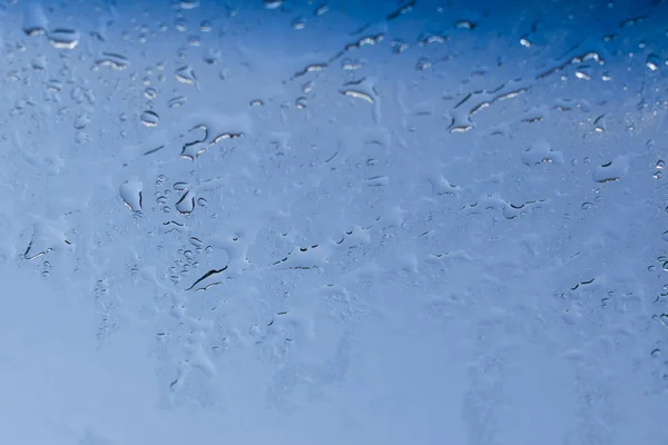 Blauer Hintergrund, natürlicher Wassertropfen auf Glas vor dem Fenster. — Stockfoto