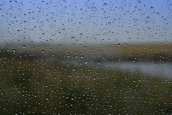Regentropfen auf das Glas mit natürlichem Hintergrund außerhalb des Fensters. — Stockfoto