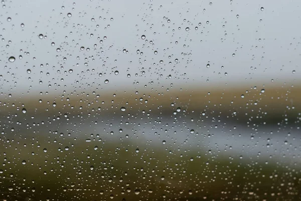 Natural landscape outside the window with rain drops on the glass.